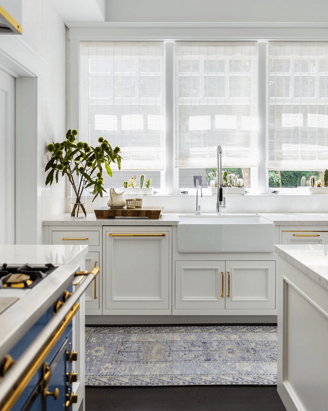 a-modern-white-kitchen-with-statement-brass-hardware-and-with-greenery