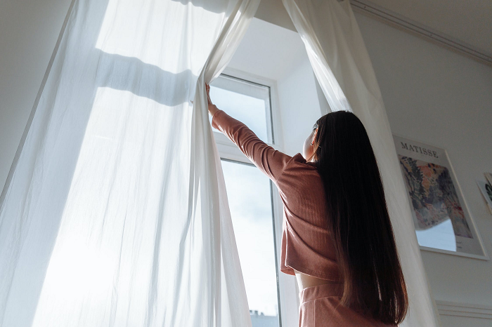 Woman-Opening-a-Window-to-Let-in-Fresh-Air-to-make-home-smell-good